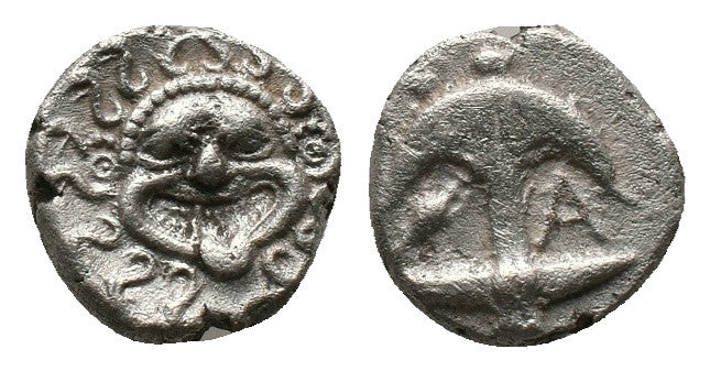 front and back of ancient greek silver coin with gorgon on one side and upside down anchor on the other