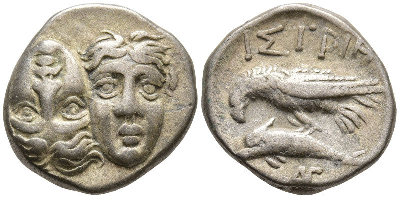 Front and Backside of ancient silver greek  istrus coin with inverted  faces on one side, and sea-eagle clutching dolphin with  inscriptions on other side